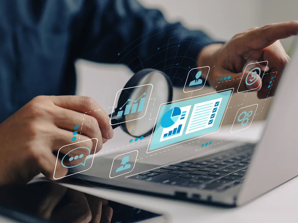 Person using magnifying glass to analyze data visualizations on a laptop screen.