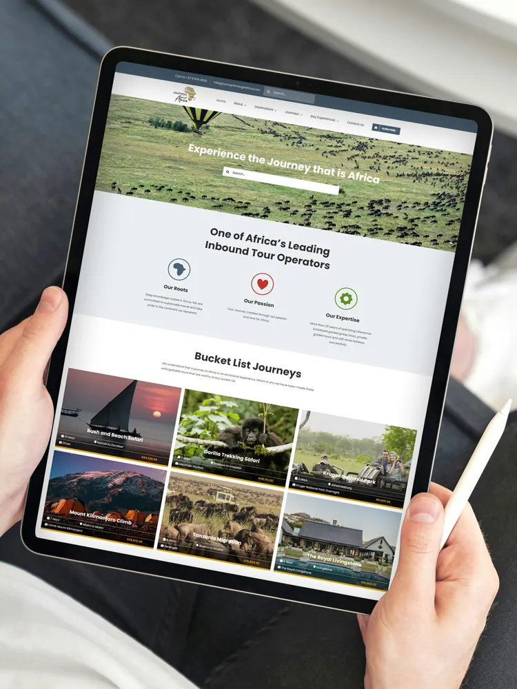 Tablet showing travel website design for "Journeys Through Africa" featuring African safari tours and bucket list adventures.